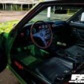 A view through the driver's side door of a green Toyota Celica Mk1