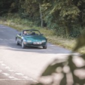 A distance shot of the front of a green Mazda MX 5 driving