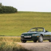 A shot of a green Mazda MX 5 convertible with a green field backdrop