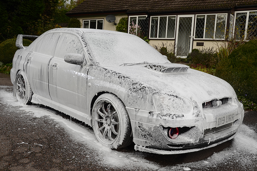 A Subaru covered in snow foam.