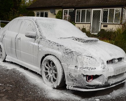 A Subaru covered in snow foam.