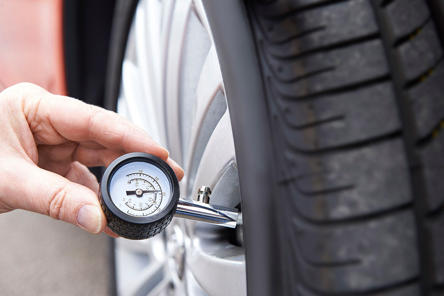 Cheap tuning tips - close-up of man checking car tyre pressure with gauge