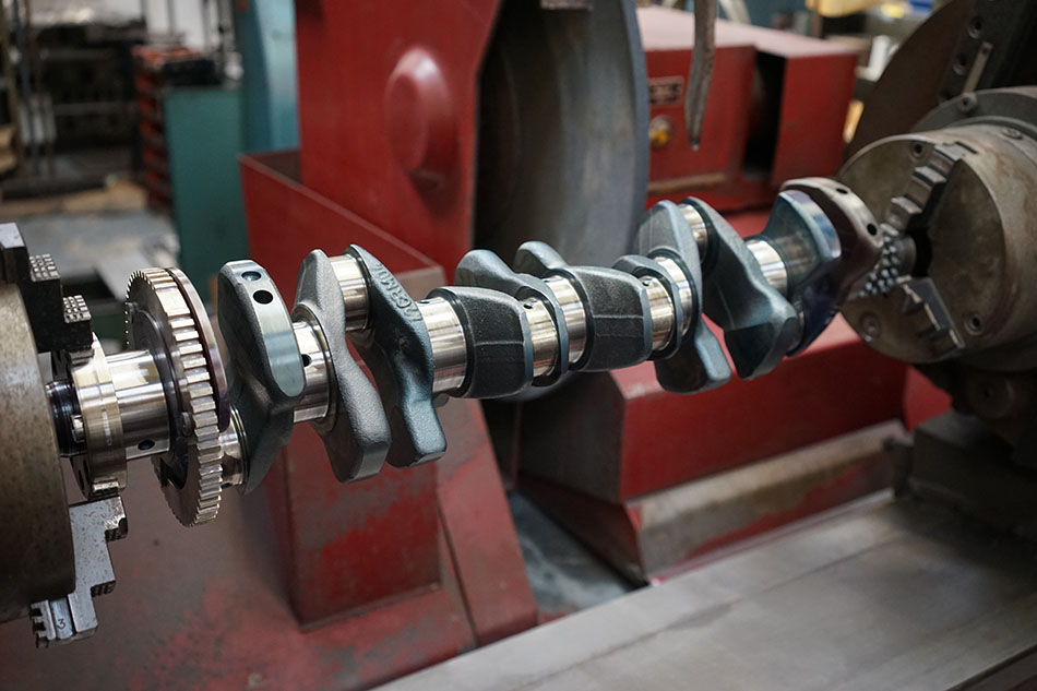 A grey and silver crankshaft in a car garage