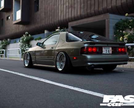 Rear left shot of a murky green tuned Mazda RX 7 FC Japana