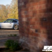 A red brick wall with a silver Porsche 964 behind