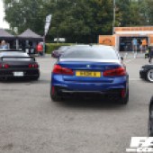 Central rear shot of a bright blue BMW M5 with the Bristol detailing stall behind