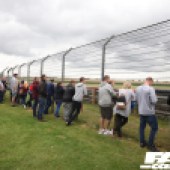 Spectators stood along a tall wire fence next to the racetrack at the Forge Action Day 2019