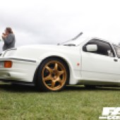 Low left side shot of a white Cosworth with gold alloys at the Forge Action Day 2019