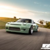 A front shot of a mint green Mazda RX 7 driving