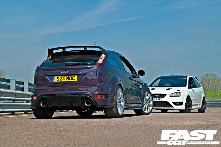 Back right shot of a purple Ford AWD Focus ST facing a white Ford Focus