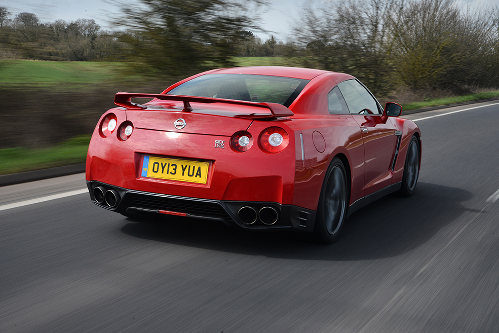 A right rear shot of a red Nissan GT R R35 driving