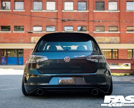 Central rear shot of a modified Mk7 Golf GTI on Air with a red brick building behind