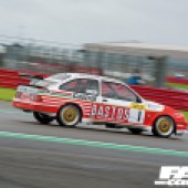 Right side shot of a red and white Ford Sierra RS500 Cosworth driving on a race track