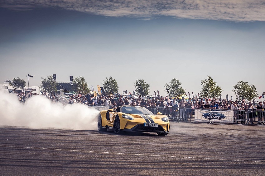 Yellow Ford GT leaving trail of smoke with the crowds