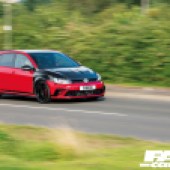 A right side driving shot of black and red tuned VW Golf GTI Mk7