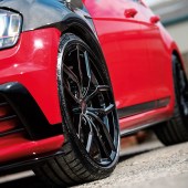 A low close up shot of the front left wheel of a black and red tuned VW Golf GTI Mk7