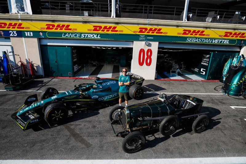 Sebastian Vettel poses with Aston Martin race cars of the present and the past.