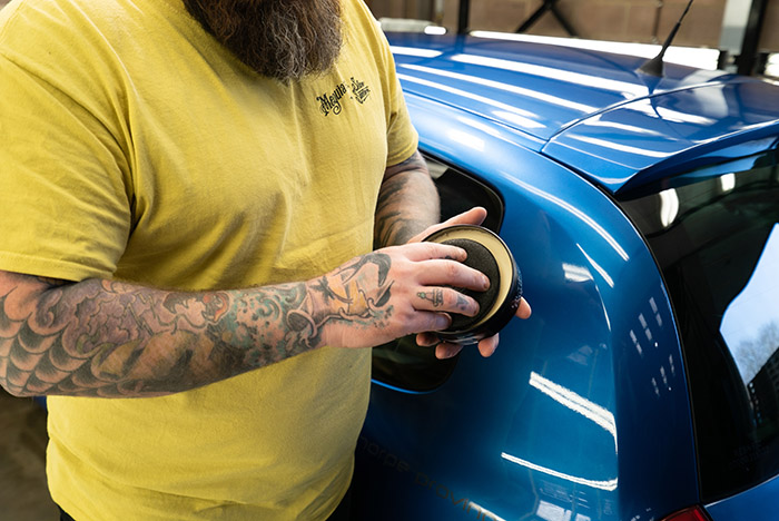 Using an applicator to apply paste wax to a car