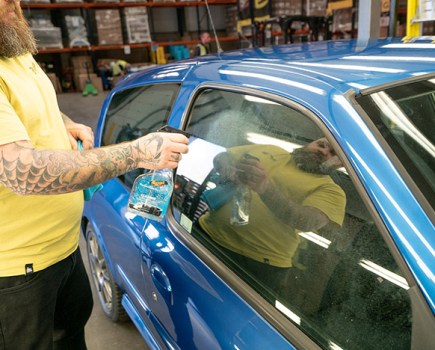 Spraying glass cleaner on car windows