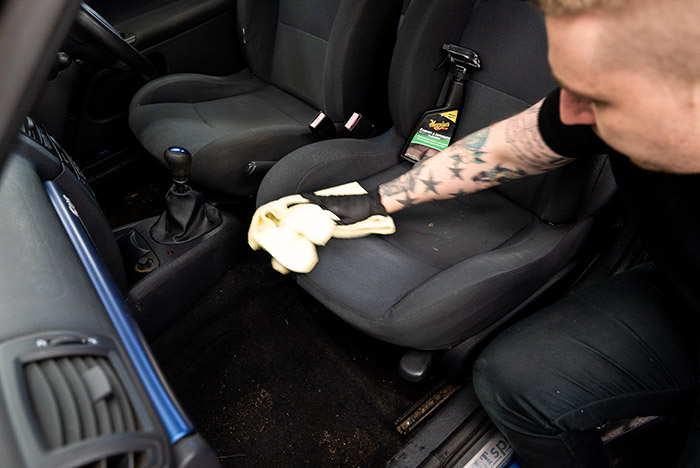 Wipe away excess upholstery cleaner from seat on car's interior