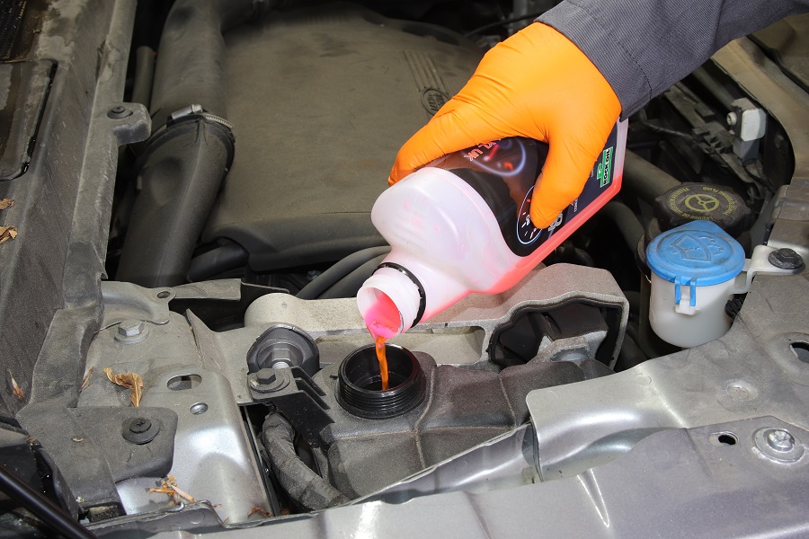 Someone adding coolant into a car's reservoir