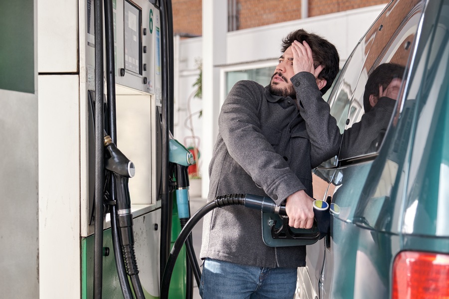 A man fills up his car, exasperated at the pump price.
