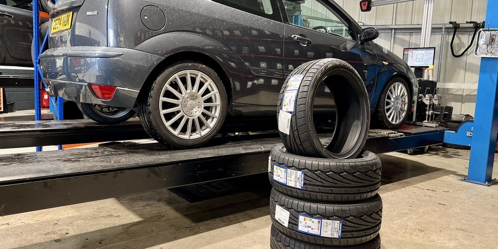 stack of tyres placed in front of grey Ford Focus ST170