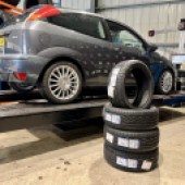 stack of tyres placed in front of grey Ford Focus ST170