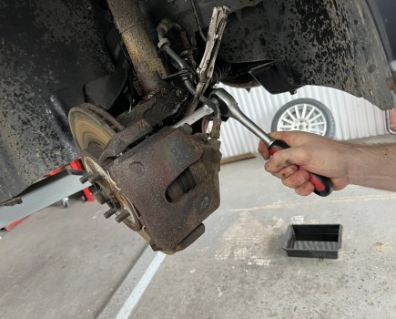 Socket and ratchet removing bolts from a brake caliper