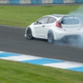 Tuned Ford Fiesta drifting at Knockhill race track with smoke coming from the tyres
