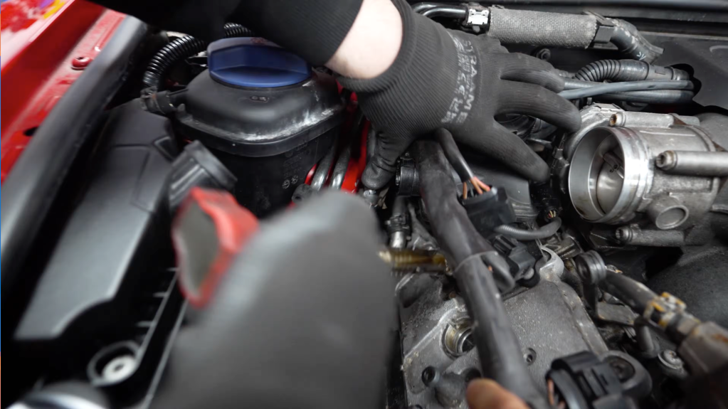 Close up of hands in an engine bay removing component parts from an Audi RS6 V10 engine