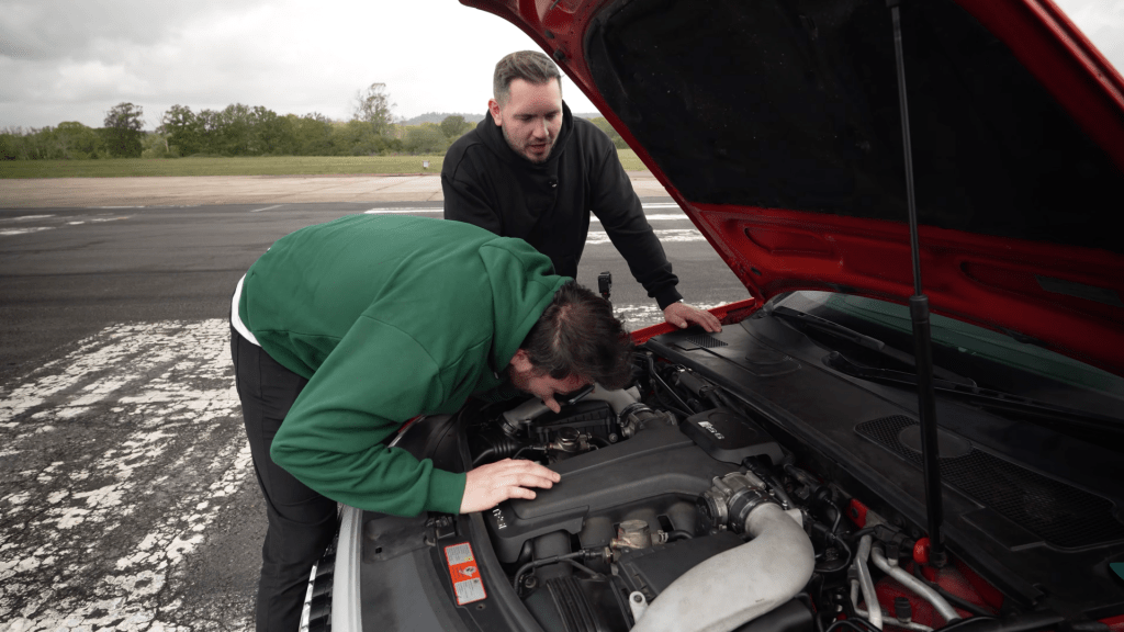 Two men looking under the bonnet of a broken Audi RS6 