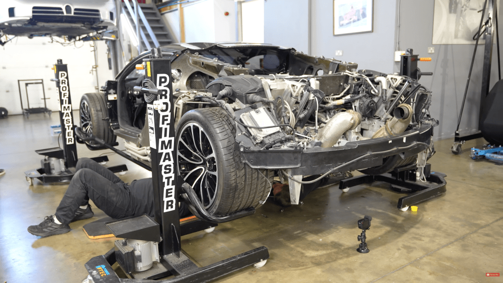 Mechanic lying underneath a boken Bugatti Veyron installing a rebuilt gearbox