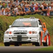 A front shot of an orange and white Escort Cosworth WRC driving