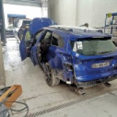 A rear view of a blue Ford Focus in a mechanics garage