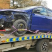 A taken apart blue Ford Fiesta on a car transporter