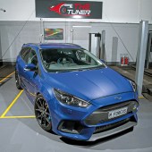 A front view of a blue Ford Fiesta under a dark grey 'The Tuner' sign