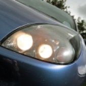 A close up of the front left headlight of a blue Ford Puma