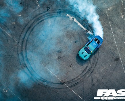 Aerial view of a bright blue James Deane E92 drift car driving donuts