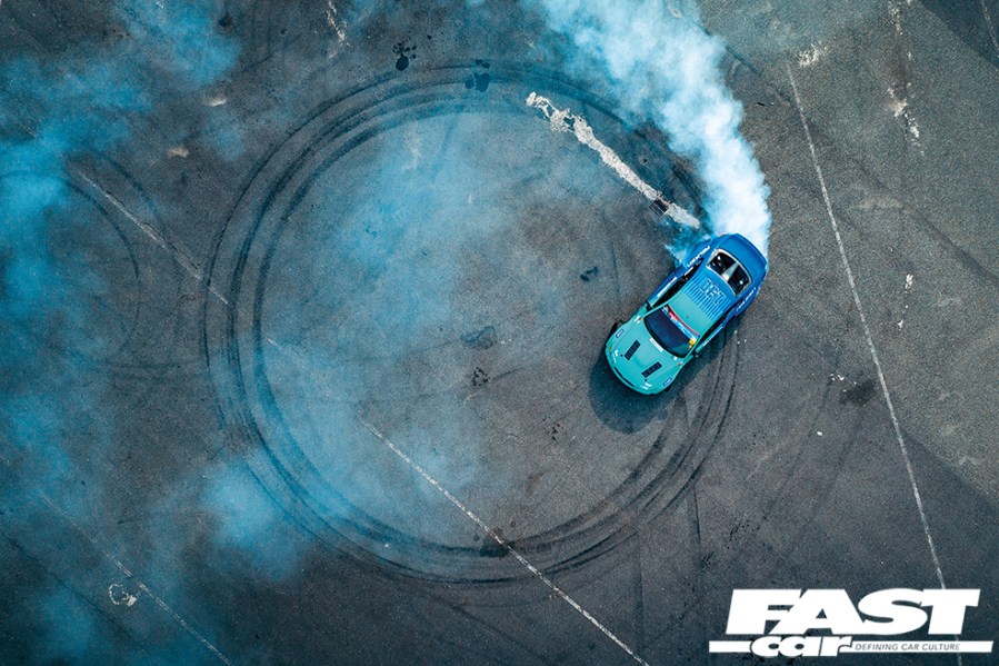 Aerial view of a bright blue James Deane E92 drift car driving donuts