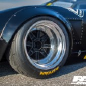 A close up of the front left wheel of a black Lamborghini Miura