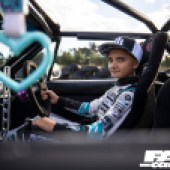 A young boy with a black and white cap sat in the driver's seat of a Mazda MX 5 drift car
