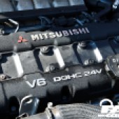 A close up of the Mitsubishi logo on the black engine inside a Mitsubishi 3000 GT