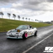 A front left shot of a white Mazda MX 5 drift car driving on a race track