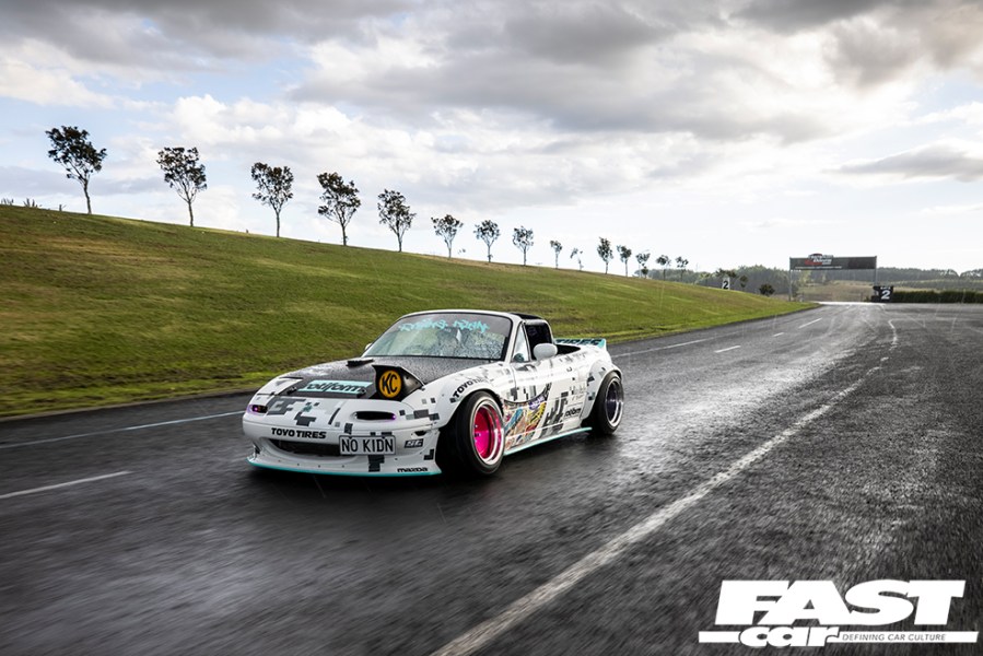 A front left shot of a white Mazda MX 5 drift car driving on a race track