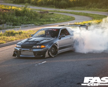 The front left side of a grey modified Nissan Skyline R32 GT R with a smoking back left wheel