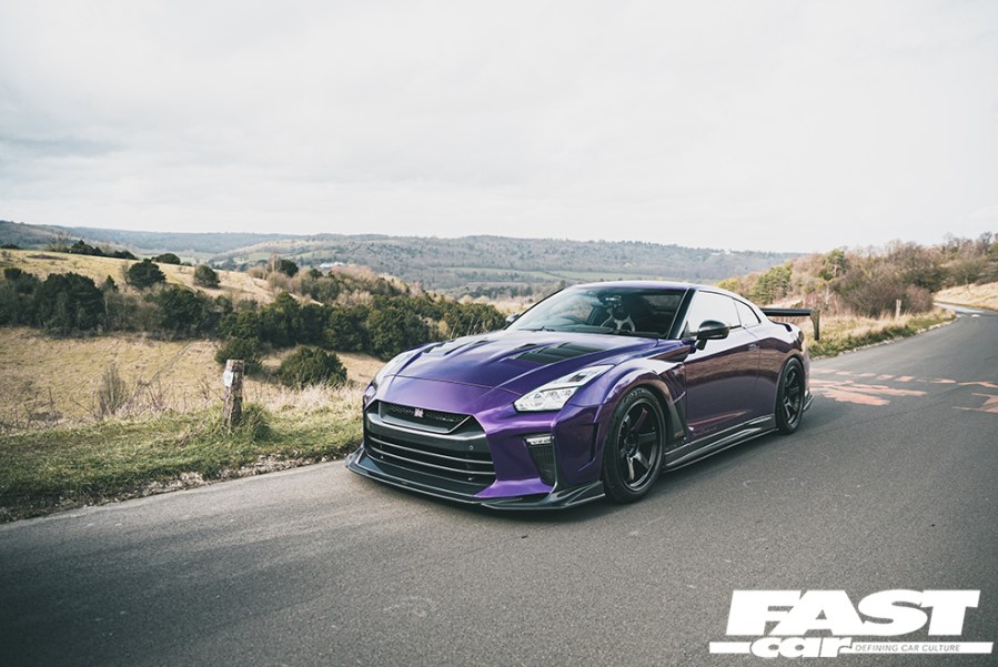 A front left shot of a purple Nissan GT R driving on a country road
