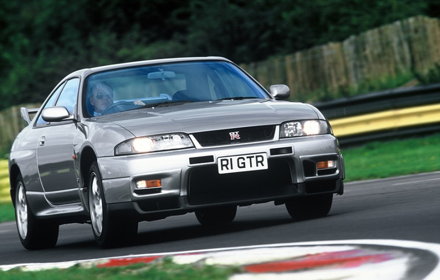 Close up frontal shot of a silver Nissan Skyline GT R R33 driving on a race track