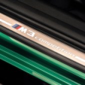 The M3 symbol on the inner door frame of a green BMW M3 Sedan