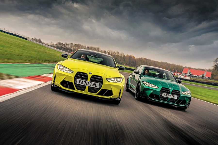 A frontal shot of a lime green and an emerald green BMW M3 driving parallel on a race track